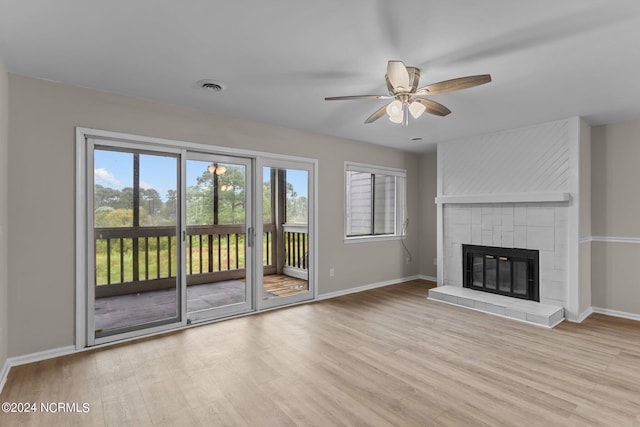 unfurnished living room with ceiling fan, light wood-type flooring, and a tile fireplace