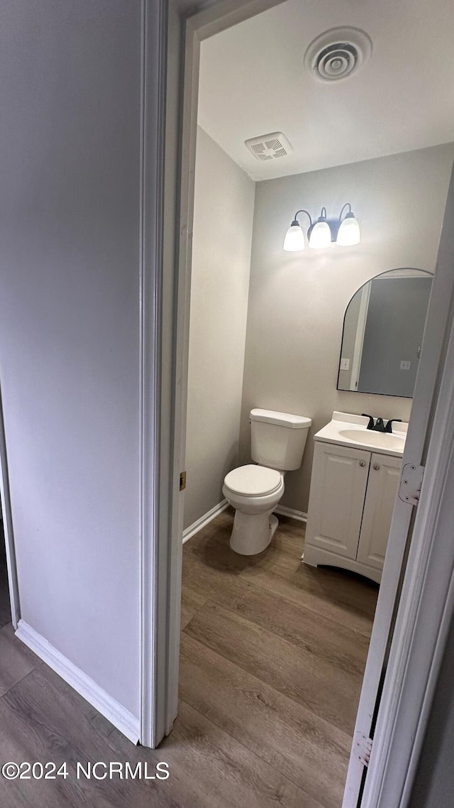 bathroom with hardwood / wood-style flooring, toilet, and vanity