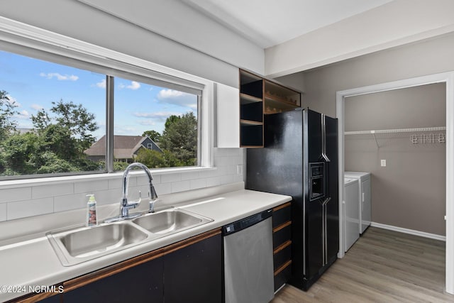 kitchen with independent washer and dryer, hardwood / wood-style flooring, dishwasher, sink, and backsplash