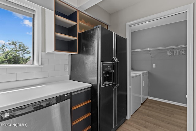 kitchen featuring decorative backsplash, hardwood / wood-style floors, stainless steel dishwasher, black fridge with ice dispenser, and washing machine and dryer