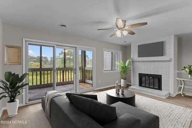 living room featuring light wood-type flooring, plenty of natural light, and a tile fireplace