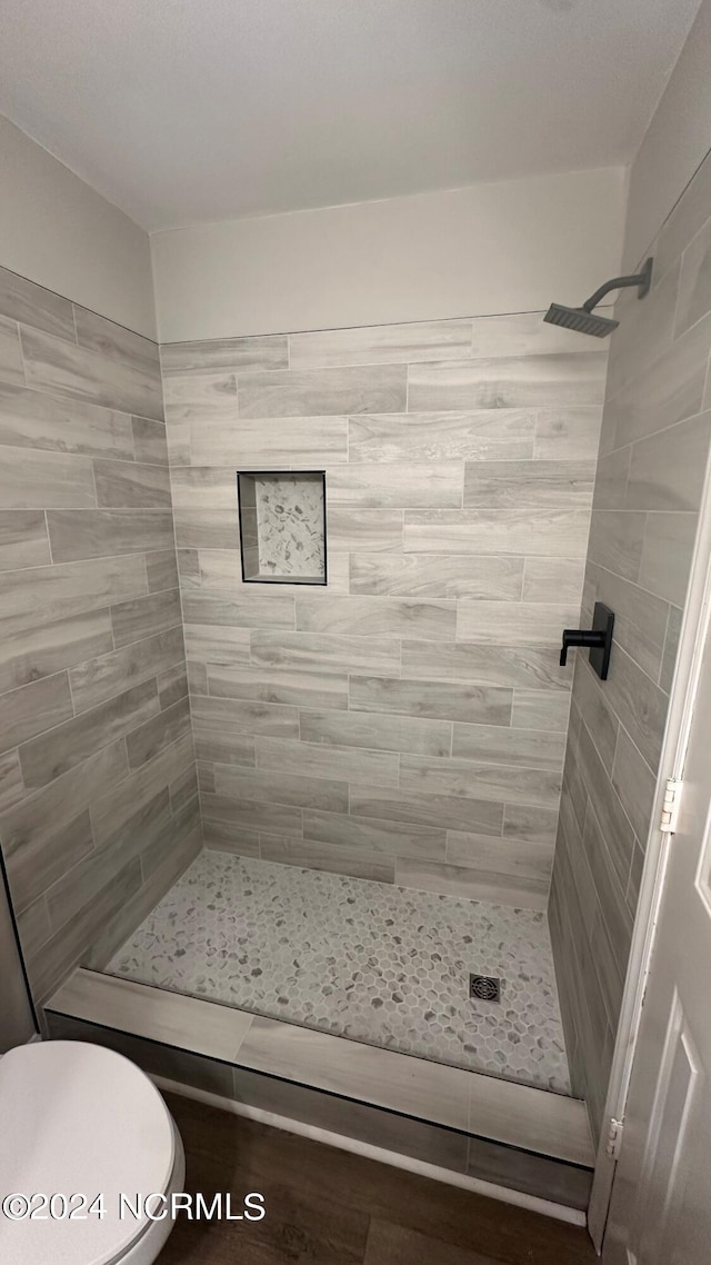 bathroom featuring tiled shower and toilet