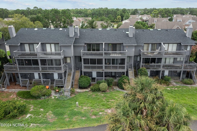 back of property with a balcony and a lawn