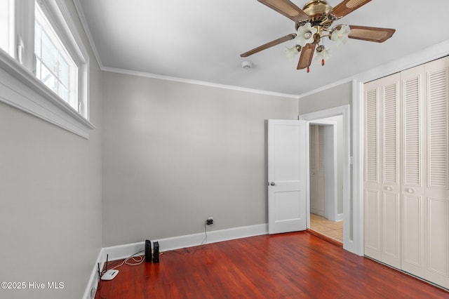 unfurnished bedroom with ornamental molding, wood-type flooring, ceiling fan, and a closet