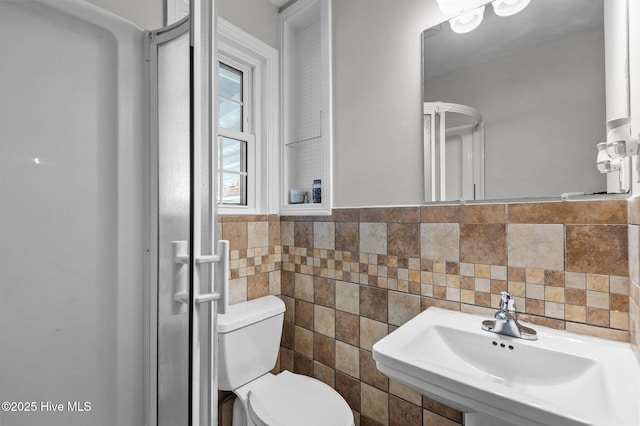 bathroom featuring toilet, sink, and tile walls