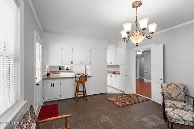 kitchen featuring hanging light fixtures, crown molding, light stone countertops, and white cabinets