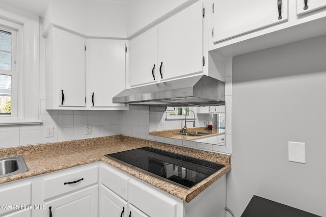 kitchen with black electric cooktop, backsplash, sink, and white cabinets