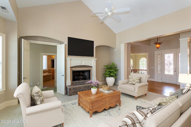 living area featuring visible vents, decorative columns, a ceiling fan, high vaulted ceiling, and a tile fireplace