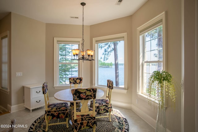 tiled dining area featuring plenty of natural light, a water view, and a chandelier