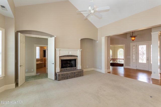 unfurnished living room featuring visible vents, a ceiling fan, a fireplace, high vaulted ceiling, and light carpet