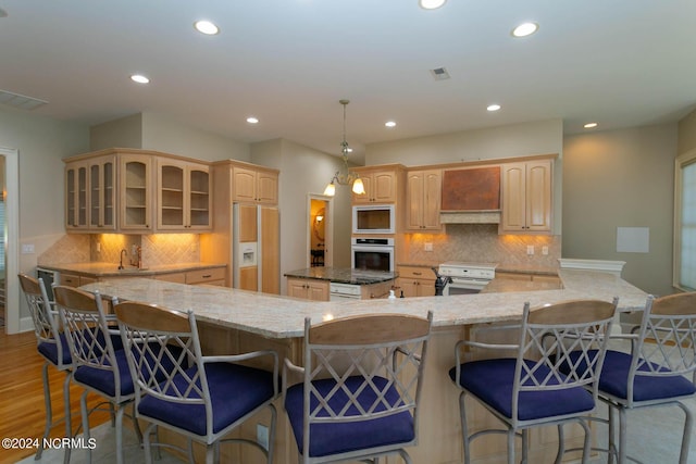 kitchen featuring glass insert cabinets, recessed lighting, premium range hood, and built in appliances