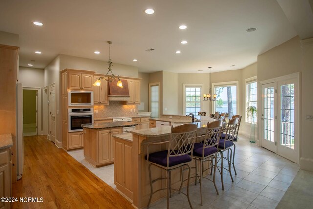 kitchen with an inviting chandelier, light hardwood / wood-style floors, oven, a kitchen island, and built in microwave