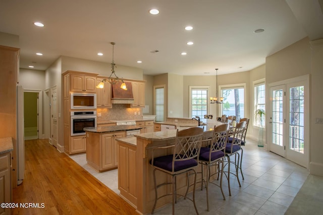 kitchen featuring oven, a notable chandelier, built in microwave, a large island, and decorative backsplash