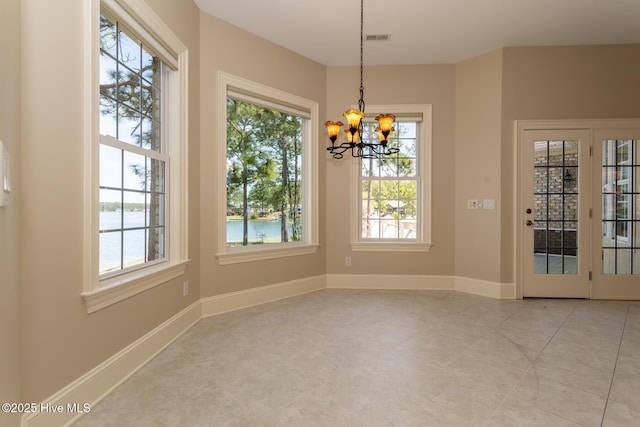 unfurnished dining area featuring a chandelier, light tile patterned floors, visible vents, and a water view