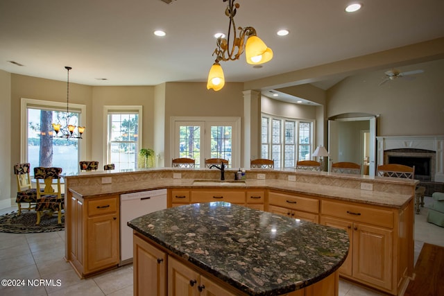 kitchen with dark stone counters, white dishwasher, sink, and an island with sink