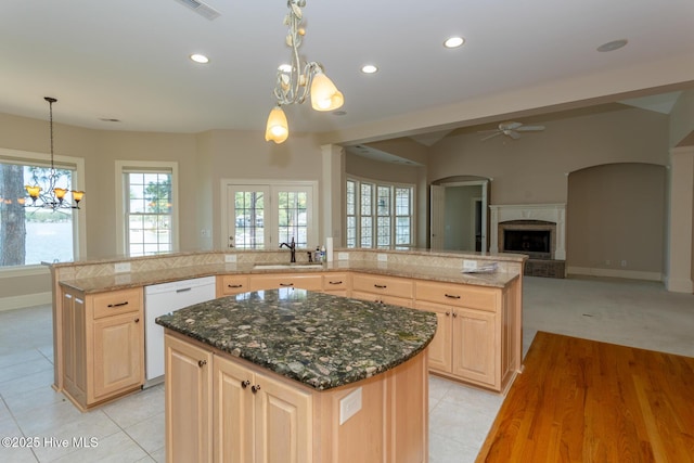kitchen with dishwasher, a large island with sink, ceiling fan with notable chandelier, a sink, and light brown cabinetry