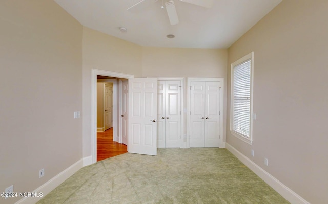 unfurnished bedroom featuring a ceiling fan, carpet, baseboards, and multiple closets