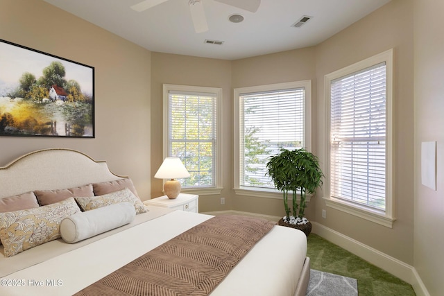 carpeted bedroom with visible vents, baseboards, and a ceiling fan