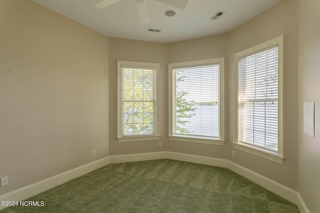 unfurnished room with visible vents, baseboards, a ceiling fan, and dark carpet