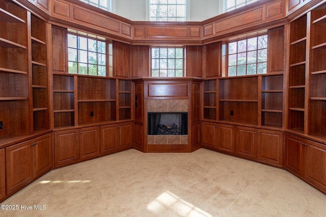 unfurnished living room with light carpet, a tile fireplace, and a high ceiling