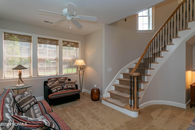 living area with baseboards, carpet flooring, a ceiling fan, stairs, and visible vents