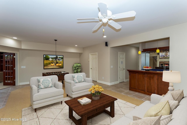 living area featuring ceiling fan with notable chandelier, light tile patterned floors, baseboards, and recessed lighting