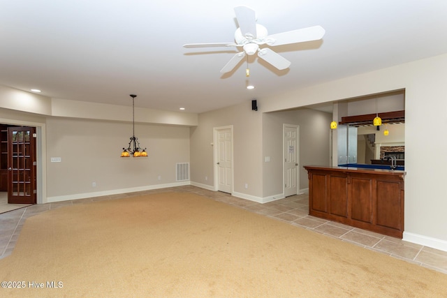unfurnished living room featuring ceiling fan with notable chandelier, light tile patterned floors, visible vents, recessed lighting, and light carpet