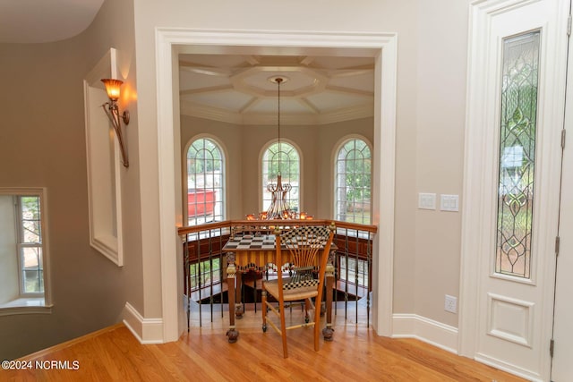 dining room featuring light wood finished floors, ornamental molding, a chandelier, coffered ceiling, and baseboards