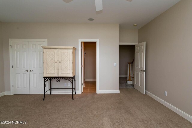 unfurnished bedroom with light carpet, a closet, and ceiling fan