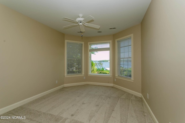 empty room featuring a ceiling fan, carpet flooring, visible vents, and baseboards