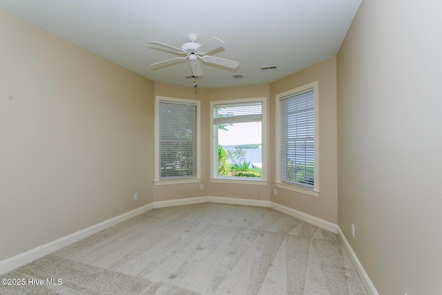 carpeted spare room with baseboards, a ceiling fan, and visible vents