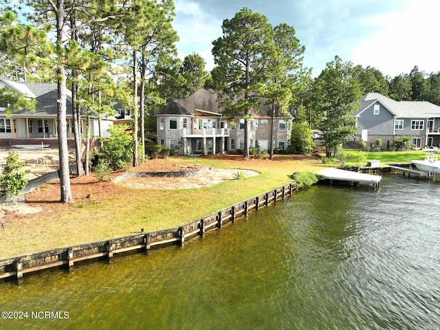 view of dock with a water view, a residential view, and a yard