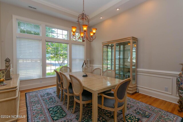 dining room featuring a tray ceiling, light hardwood / wood-style floors, a notable chandelier, and plenty of natural light