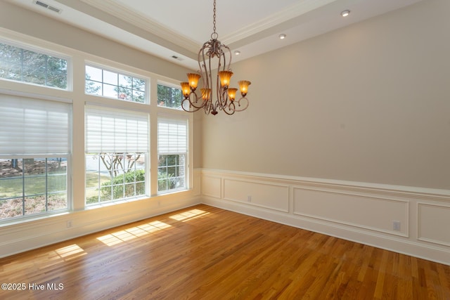 unfurnished room with ornamental molding, light wood-style flooring, a notable chandelier, and visible vents