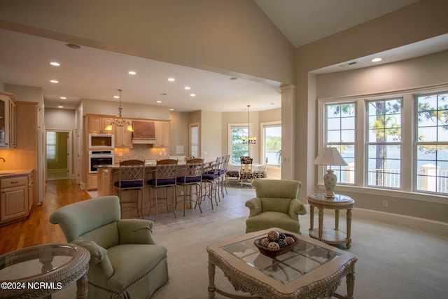 living room featuring recessed lighting, lofted ceiling, ornate columns, an inviting chandelier, and baseboards