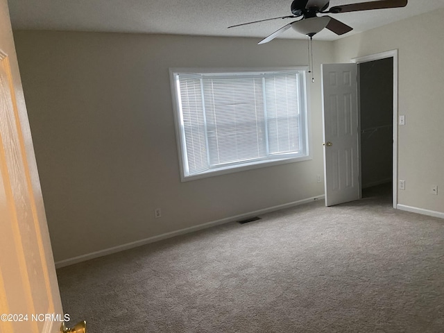 unfurnished bedroom featuring carpet flooring, a walk in closet, ceiling fan, a textured ceiling, and a closet