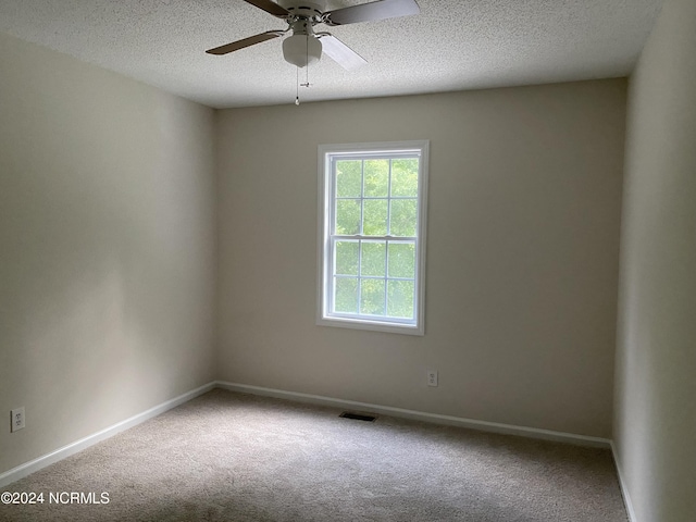 carpeted spare room featuring ceiling fan and a textured ceiling