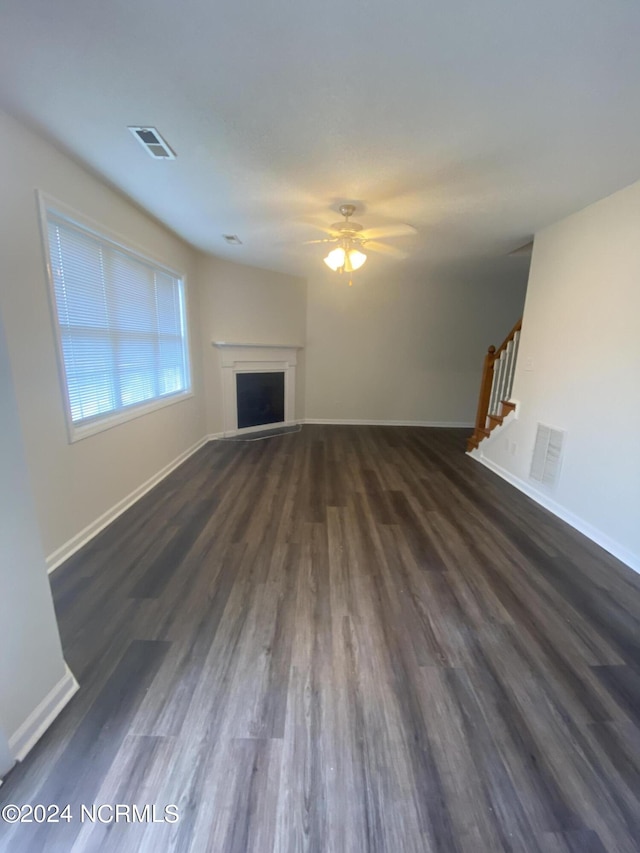 unfurnished living room with ceiling fan and dark hardwood / wood-style flooring