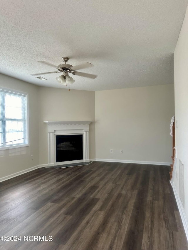 unfurnished living room with ceiling fan, dark hardwood / wood-style floors, and a textured ceiling