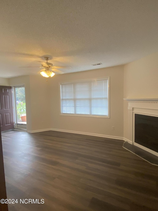 unfurnished living room with ceiling fan, dark hardwood / wood-style floors, and a textured ceiling