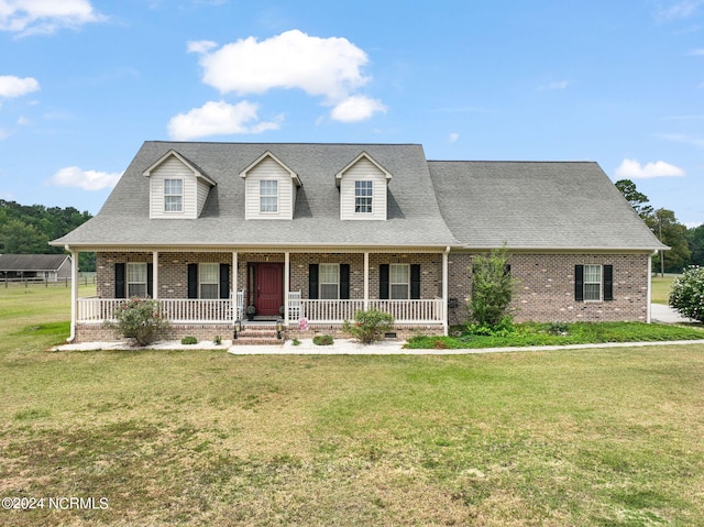 new england style home featuring a porch and a front lawn