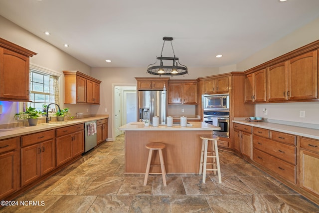 kitchen with pendant lighting, sink, appliances with stainless steel finishes, a center island, and a kitchen bar