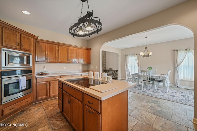 kitchen featuring appliances with stainless steel finishes, a chandelier, an island with sink, and hanging light fixtures