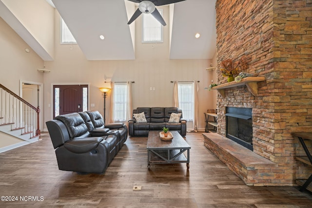 living room featuring dark hardwood / wood-style flooring, a stone fireplace, and ceiling fan