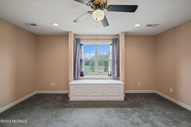 unfurnished room with ceiling fan and dark carpet