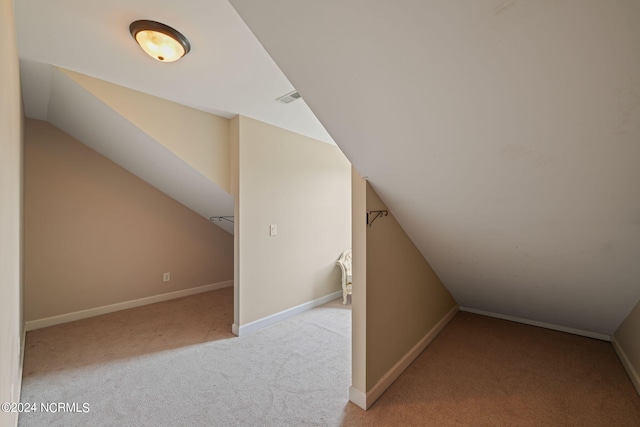 additional living space featuring light carpet and vaulted ceiling