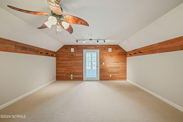 additional living space featuring ceiling fan, lofted ceiling, carpet flooring, and wooden walls