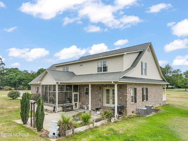 rear view of house featuring french doors, a patio area, central AC unit, a yard, and a sunroom