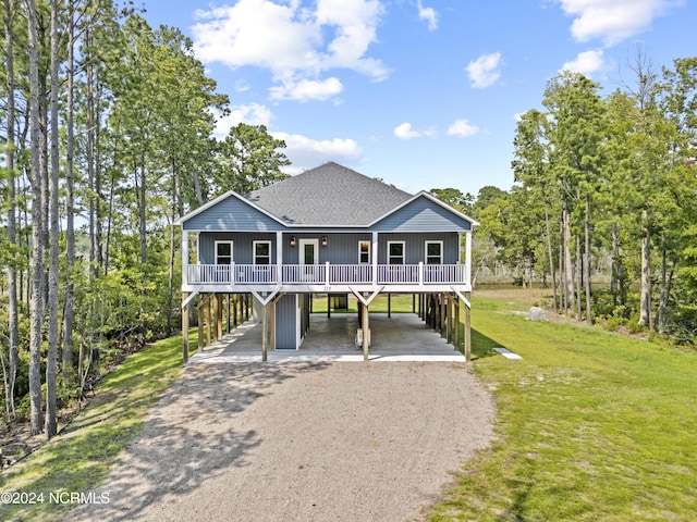 beach home featuring a front lawn, a carport, and covered porch