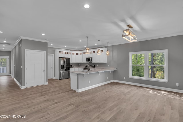 kitchen with pendant lighting, a breakfast bar area, white cabinetry, stainless steel appliances, and kitchen peninsula